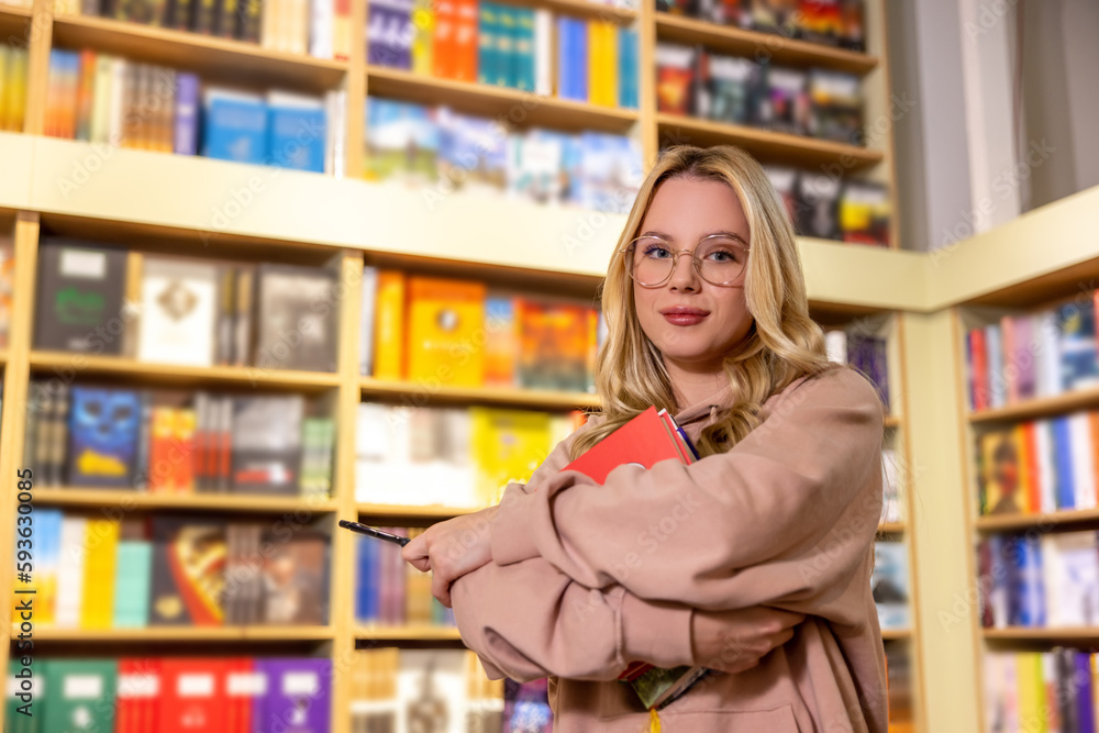 Pretty blonde woman standing with books in library Pretty blonde woman standing with books in library