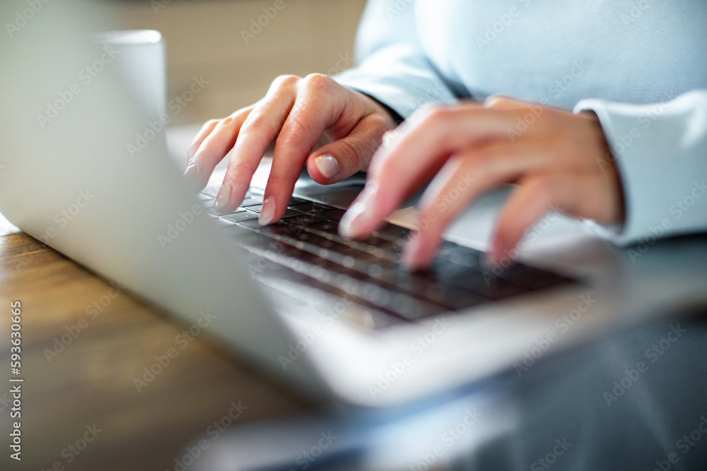 Young adult woman working on her laptop in the kitchen of her home Young adult woman working on her laptop in the kitchen of her home