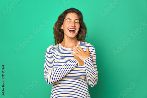 Young caucasian woman isolated laughing keeping hands on heart, concept of happiness. © Asier