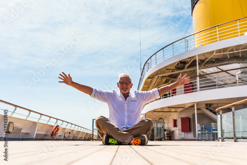 happy handsome middle aged man posing sitting on the deck of a cruise ship