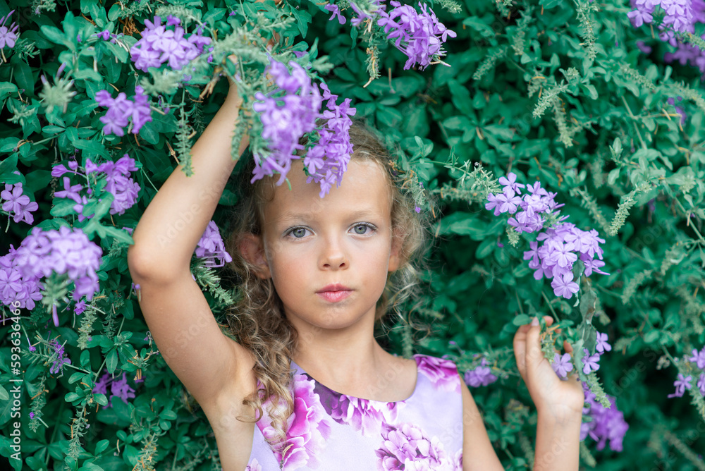 The girl in the holiday purple dress by the bush with the purple flowers. High quality photo The girl in the holiday purple dress by the bush with the purple flowers. High quality photo