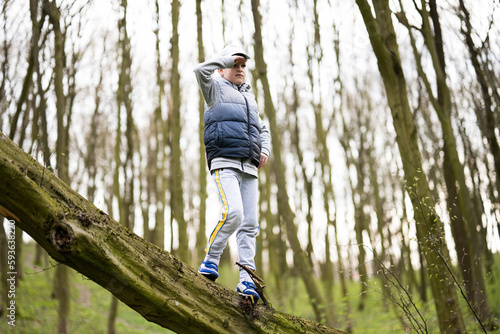 Boy climbed a felled tree in spring forest. Happy childhood moments.