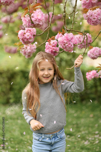 A girl, smelling a branch of a cherry blossom tree photo