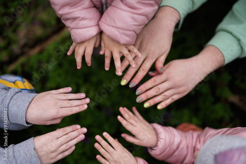 Close up of hands and fingers of mother with kids in spring forest background.