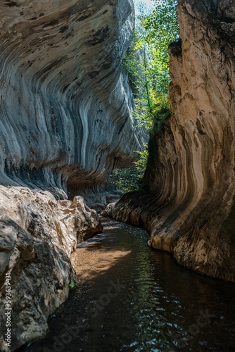 Vertical shot of the narrow river flowing between the rocks in canyon