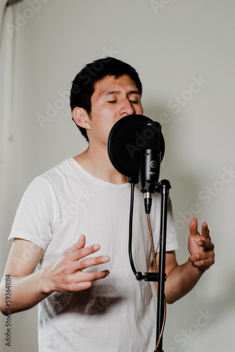 Photograph of male singer in a recording studio with dramatic lighting in the background. Concept of people  music and arts.
