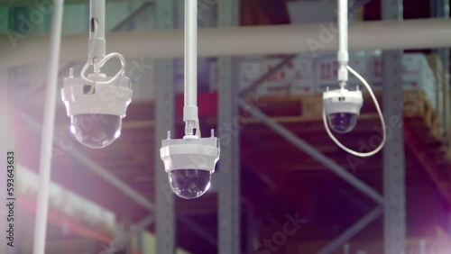 Three panoramic cameras suspend from ceiling in warehouse. Panoramic cameras record activity in storehouse at present time