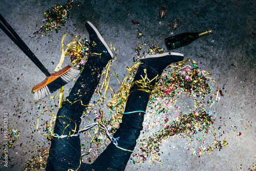 Crop drunk man with confetti on floor during party