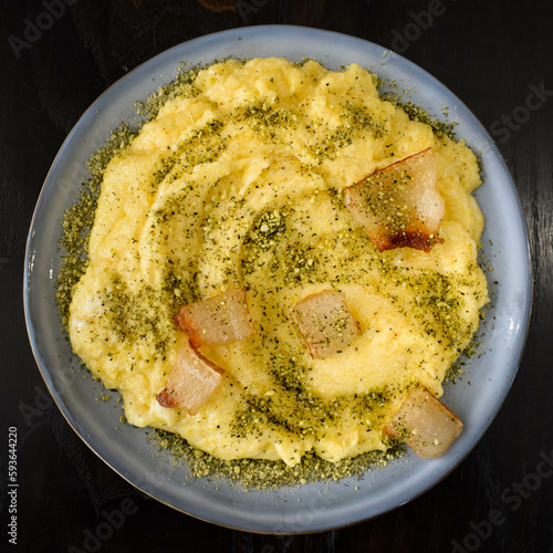 Creamy Italian polenta with bacon, pork crackers or pancetta, sprinkled with spices,