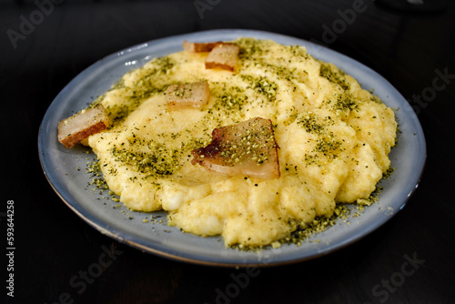 Creamy Italian polenta with bacon, pork crackers or pancetta, sprinkled with spices,