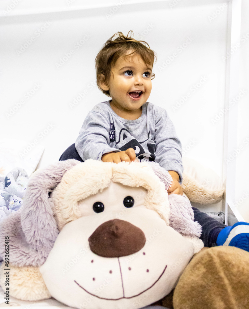Baby playing at home curious with expression of contented surprise in her amusement. Mention children's play and motor and brain development and the importance of this phase. Baby playing at home curious with expression of contented surprise in her amusement. Mention children's play and motor and brain development and the importance of this phase.
