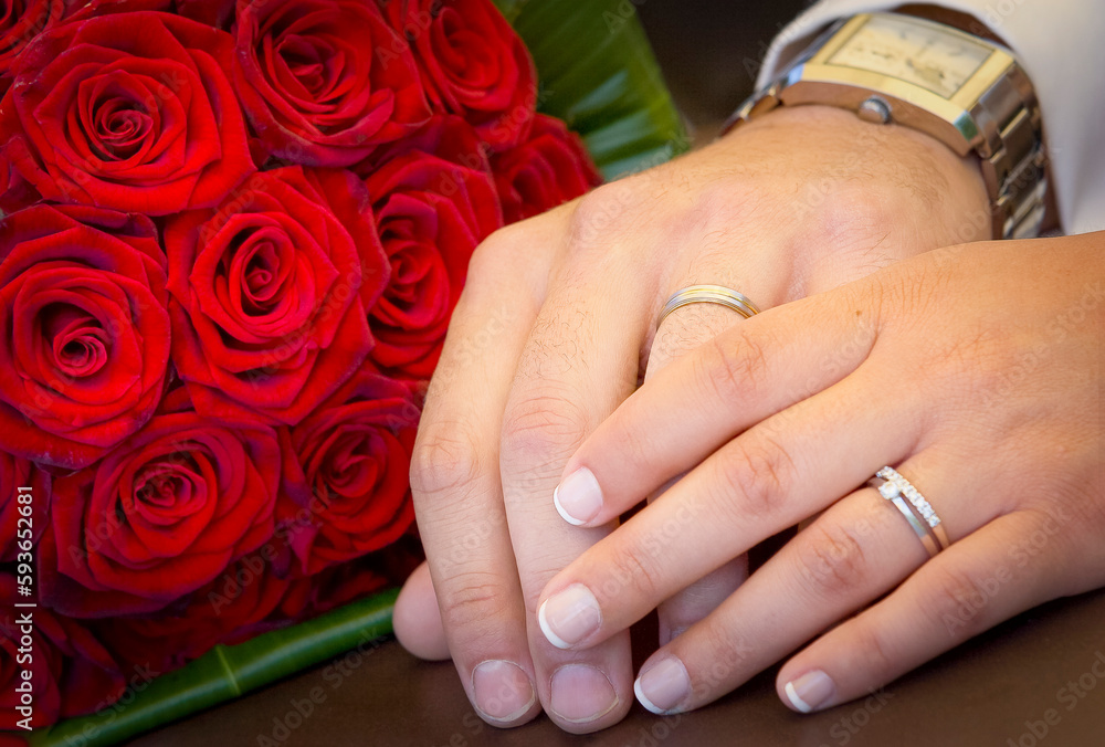 Groom and the bride with white wedding bouquet outdoors close-up. Hands with wedding rings. Close-up on the hands of a Caucasian couple holding the bridegroom roses bouquet. Wedding day. Groom and the bride with white wedding bouquet outdoors close-up. Hands with wedding rings. Close-up on the hands of a Caucasian couple holding the bridegroom roses bouquet. Wedding day.