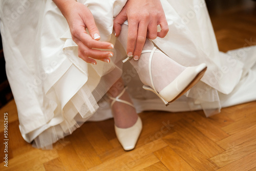 The bride puts on her shoes. Bride wearing shoes.  Beautiful bride is getting ready for her wedding. Wedding shoes. the bride puts on her shoes in the morning. Wedding Day.