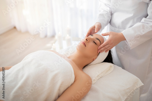Portrait of relaxed young woman having facial massage in spa center