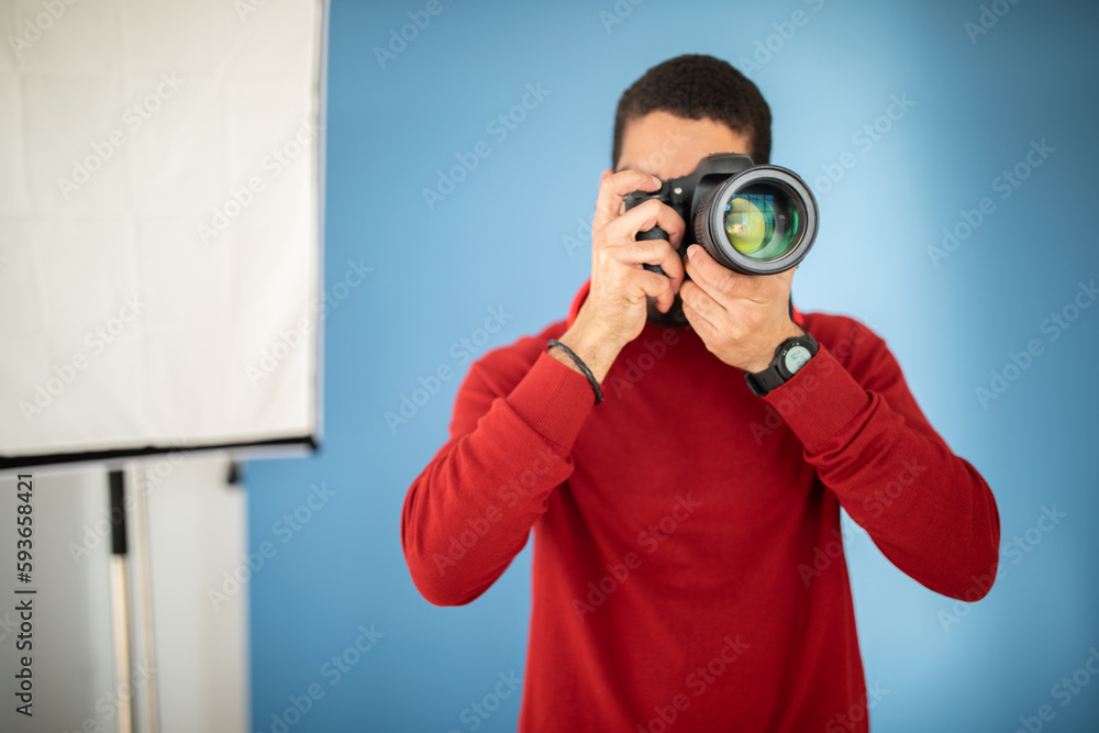 Male photographer taking photo with digital camera in studio Male photographer taking photo with digital camera in studio