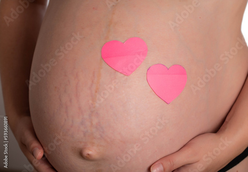 Wallpaper Mural Big belly of a pregnant girl with two pink hearts. The concept of the birth of a child, love and motherhood. Copy space for text Torontodigital.ca