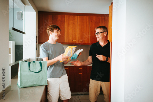 Father and son unpacking groceries in kitchen together photo