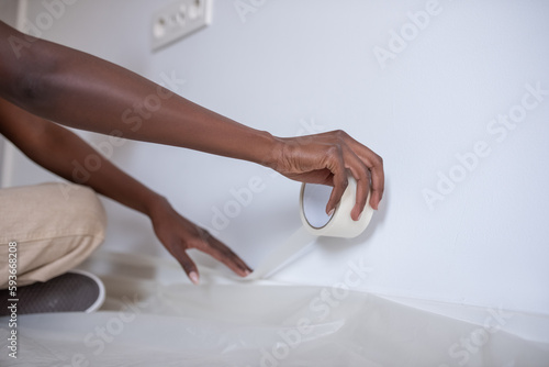 Crop black painter attaching tape near film