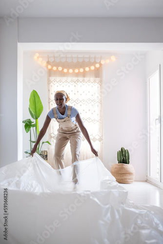 Happy black painter laying film on floor