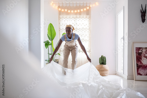 Black painter covering floor with film