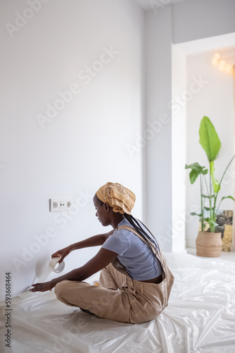 African American woman sticking painter tape near floor