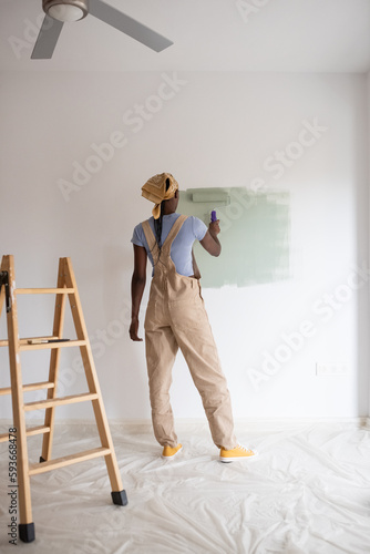 Black female painting white wall