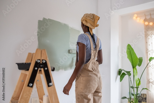 Black painter changing wall color near ladder