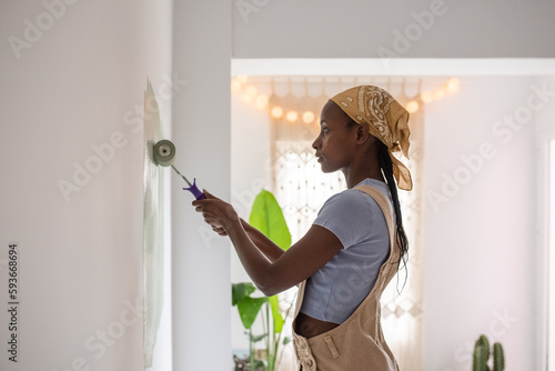 African American female painting wall in light room