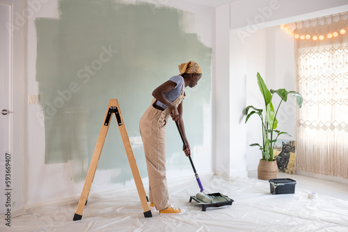 African American woman dipping roller in paint