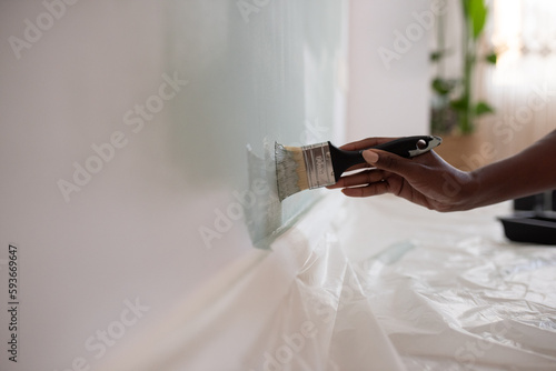 Crop African American woman painting wall