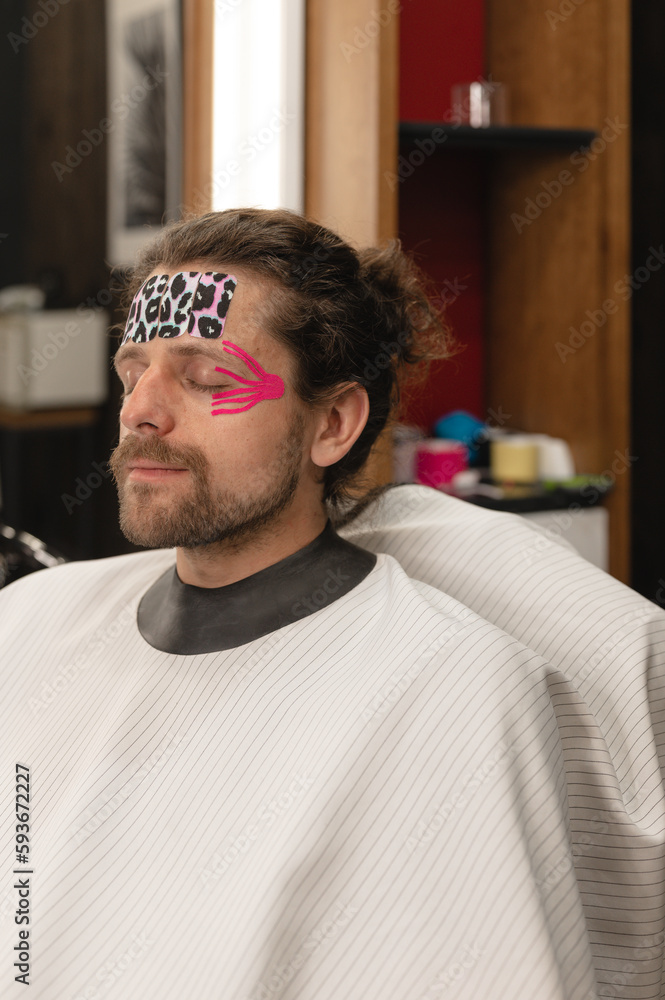 Bearded man with kinesio tapes on face Bearded man with kinesio tapes on face