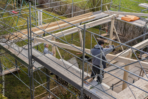 Fényképezés Two young carpenters building a carport