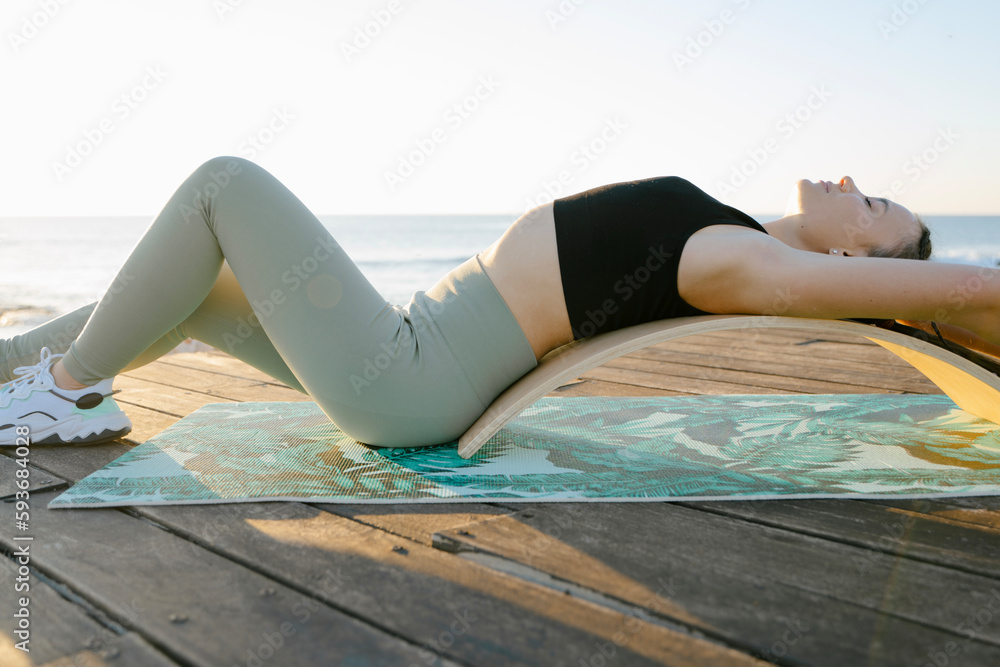 young girl doing exercises for her back on rocker board young girl doing exercises for her back on rocker board