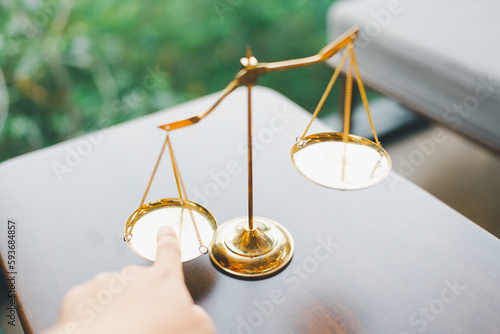 Fotografia Tip the scales of justice concept as a the hand of a person illegally influencing the legal system for an unfair advantage