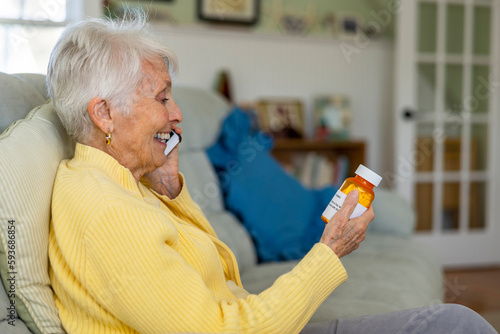 Senior Citizen on couch with prescription pill drug talking on phone photo