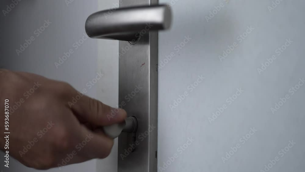 Hand unlocking the white door and then locking it again Hand unlocking the white door and then locking it again
