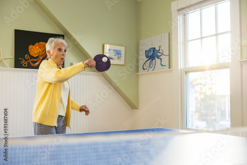 Pretty Senior Citizen lifestyle woman playing ping pong game at home 
