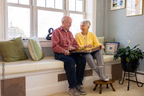 Senior Citizen couple retired  at home laugh at family photo album 