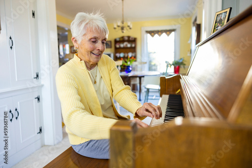 Happy talented Senior Citizen woman at Home playing piano keyboard  photo