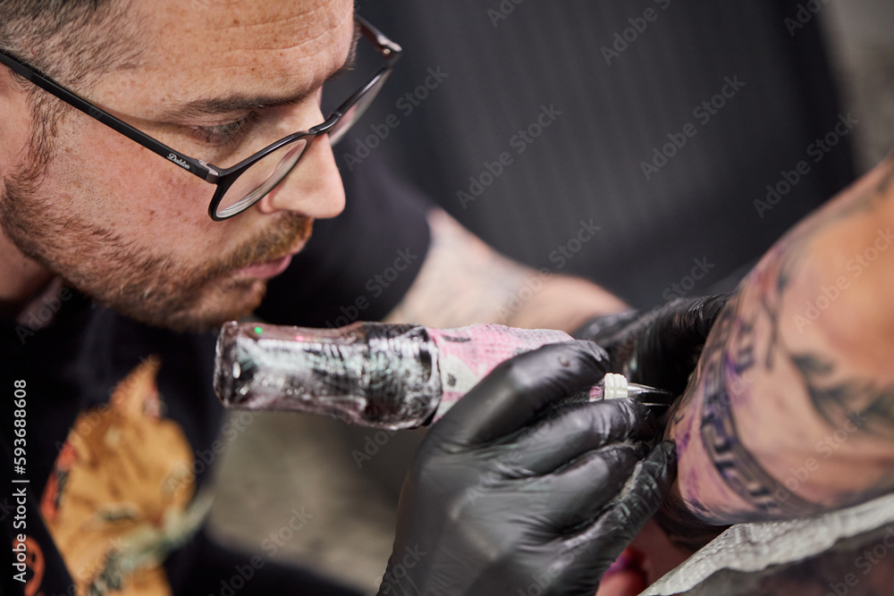 Tattoo of a lion on the arm of the client in the salon. Tattoo artist working on a client's arm in his studio.