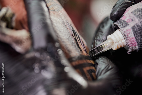 Tattoo of a lion on the arm of the client in the salon. Tattoo artist working on a client's arm in his studio.