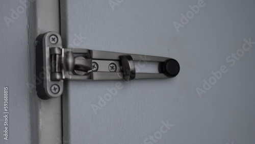 Hand locking a white door with the silver lock