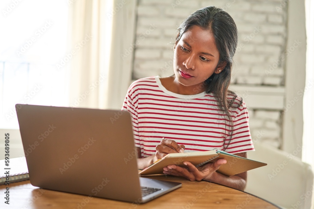 Focused Indian student working on laptop at home. Focused Indian student working on laptop at home.