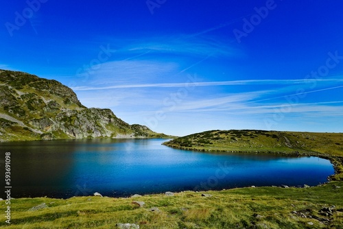 Seven Rila lakes view with green fields and mountains around, clear sky background © Segev Shoshan/Wirestock Creators