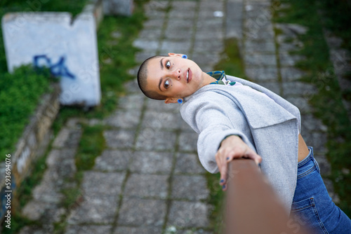 Woman in trendy outfit leaning on fence and looking over shoulder