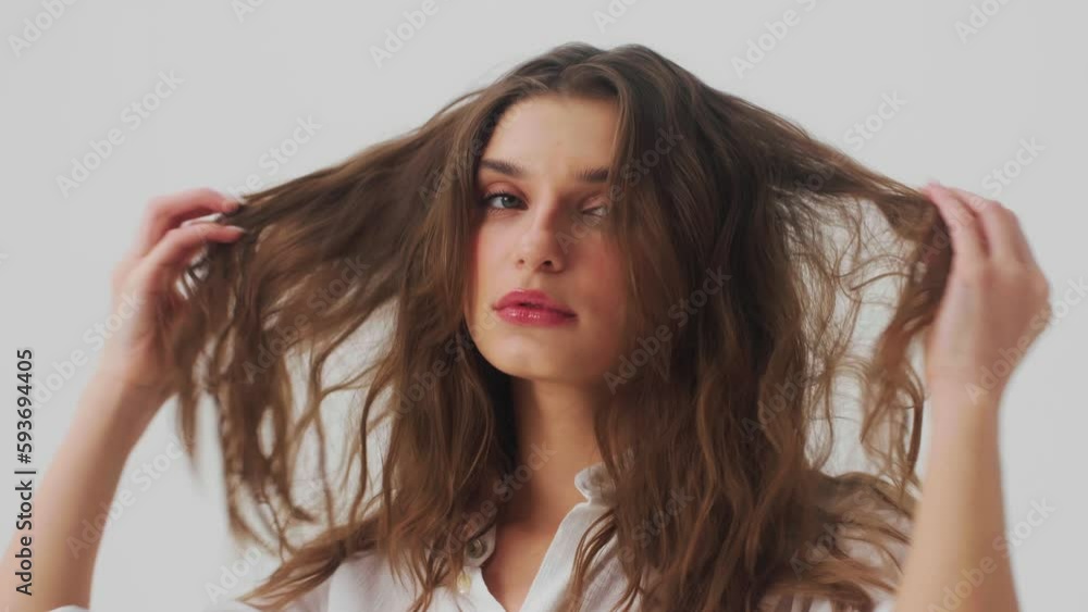 Young fashion model posing at isolated white background in studio playing with her hair Young fashion model posing at isolated white background in studio playing with her hair