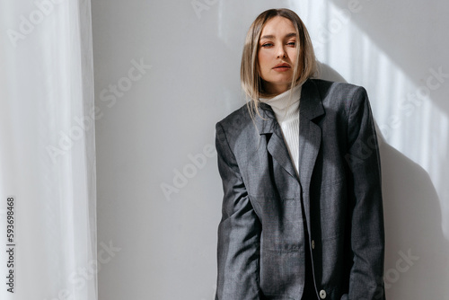 Thoughtful woman in jacket looking at camera in studio photo