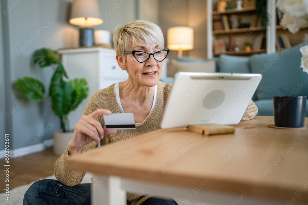Senior woman caucasian female hold credit card online shopping at home Senior woman caucasian female hold credit card online shopping at home