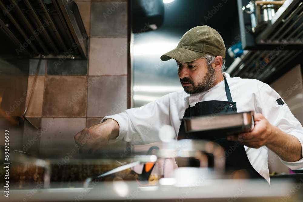 Male cook with baking pan in kitchen Male cook with baking pan in kitchen