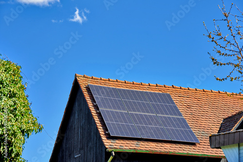 Scheunendach mit Solarzellen vor blauem Himmel photo
